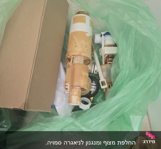 חלקי מנגנון ניאגרה ישנים שהוחלפו בתוך שקית אשפה